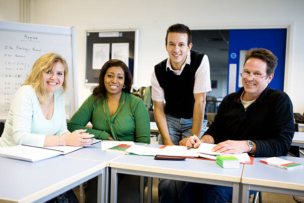 A group of mature students sit around and discuss their studies with their teacher.