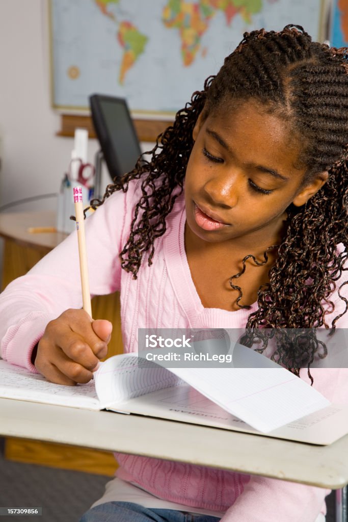 Classroom Series A young African-American girl doing homework in a classroom. Adult Stock Photo