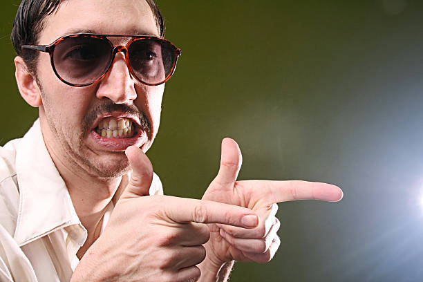 Mustache Salesman And Pointing Gesture Suspicious looking mustache guy with aviators on an olive green background, pointing at someone.  horizontl with copy space. sleaze stock pictures, royalty-free photos & images