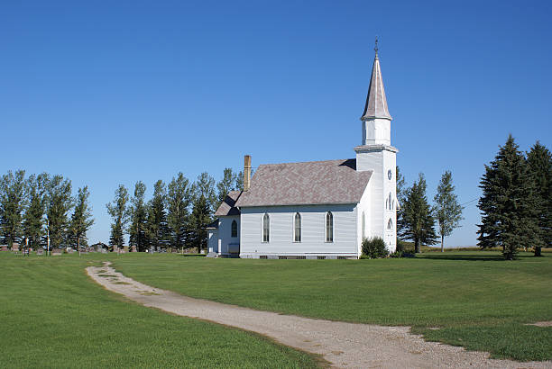 An abandoned prairie schoolhouse sitting alone on the crest of a hill.
