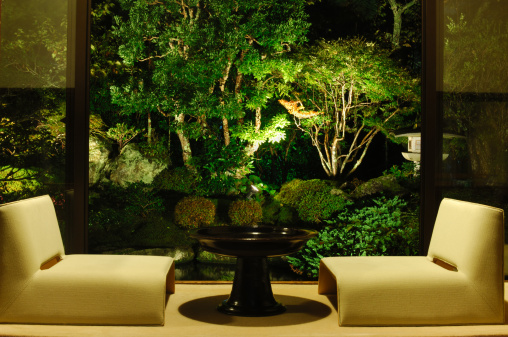 Japanese luxury room with view on a illuminated Japanese Garden and pond at night.