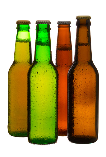 Blond beer on a green bottle closed on a wooden background close up still