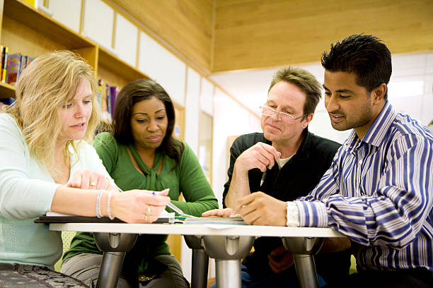 vielfältige ältere schüler arbeiten zusammen in college-bibliothek - mature student stock-fotos und bilder