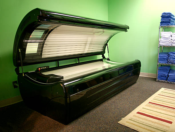 An open tanning bed in a green room Tanning bed ready to receive a customer in a health club.  tanning bed stock pictures, royalty-free photos & images