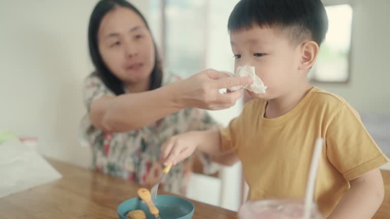 Loving Mother Wiping Her Toddler Son's Mouth Clean After Enjoyable Mealtime at Home.