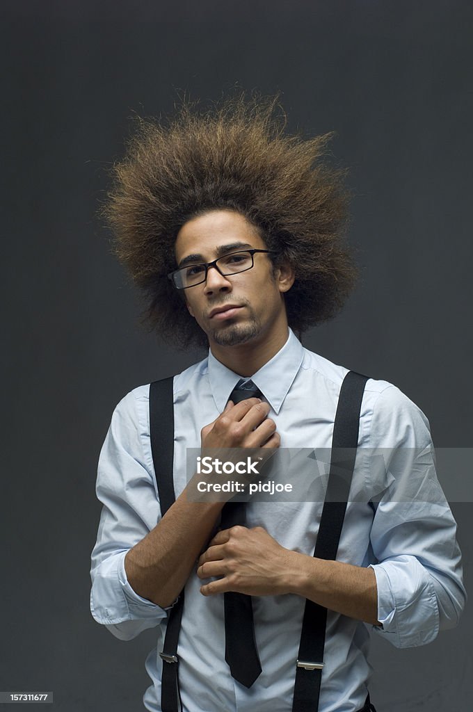 businessman with cool big hair Waist up shot of a cool funky businessman with big hair and glasses in shirt necktie and suspenders fixing his necktie looking confident at the camera Necktie Stock Photo