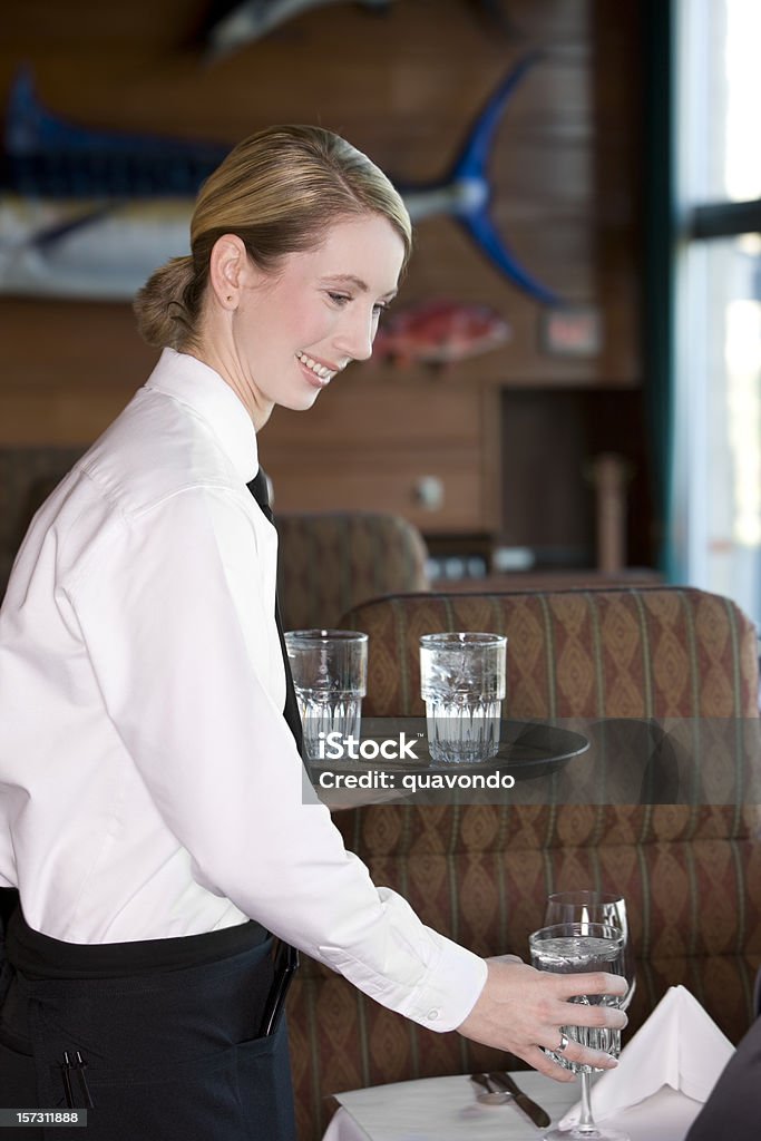 Beautiful Blond Restaurant Waitress Serving Water at Table, Copy Space Smiling server greets customer with glass of water. CLICK FOR SIMILAR IMAGES AND LIGHTBOX OF BUSINESS PEOPLE.  Restaurant Stock Photo