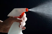 Hand squirting a red and white spray bottle on black