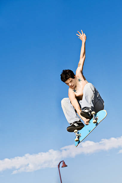 A shirtless skateboarder jumping up high in the air stock photo