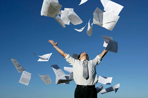 Businessman throwing papers A young businessman throwing away his papers on a blue sky background. throwing stock pictures, royalty-free photos & images