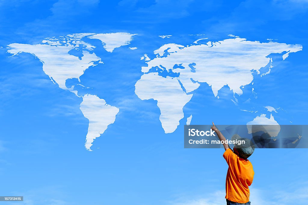 Child pointing at a sky with world map as clouds Little boy pointing at map in the clouds. World Map Stock Photo