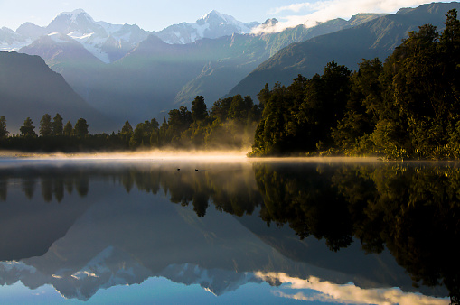 Early morning at Lake Matheson, near Fox Glacier on New Zealand's South Island.  Mount Cook and Mt Tasman, New Zealand's tallest mountains reflected in the still lake.