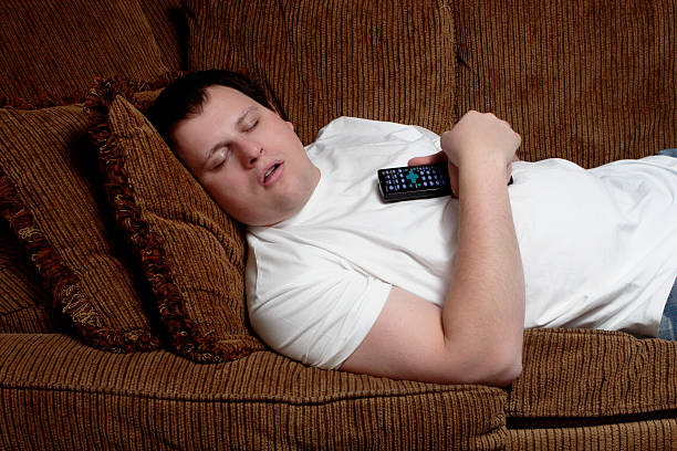 istock Man sleeping on the couch holding the remote control 157313641