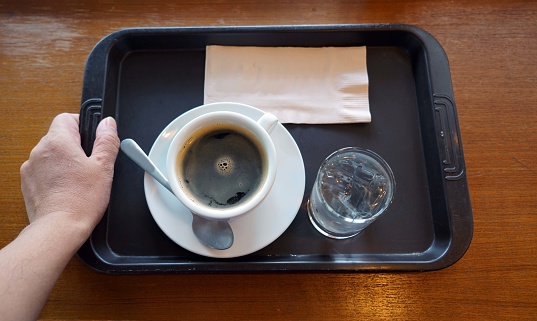 A set hot coffee cup and glass of water on the wooden table for preparing to serve.