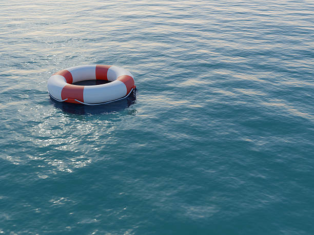 Life buoy floating on a rippled sea A life preserver in open blue water. High resolution 3D render. buoy stock pictures, royalty-free photos & images
