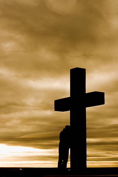 istock Man leaning on huge cross in despair against cloudy skies 157314108