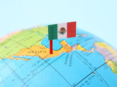 Mexican flag pointing Mexico City in cheap plastic globe. Shallow depth of field