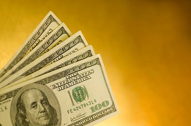 Five American one hundred dollar bills isolated on yellow stock photo