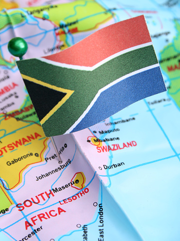 South African flag over cheap plastic map pointing Johannesburg. Shallow depth of field