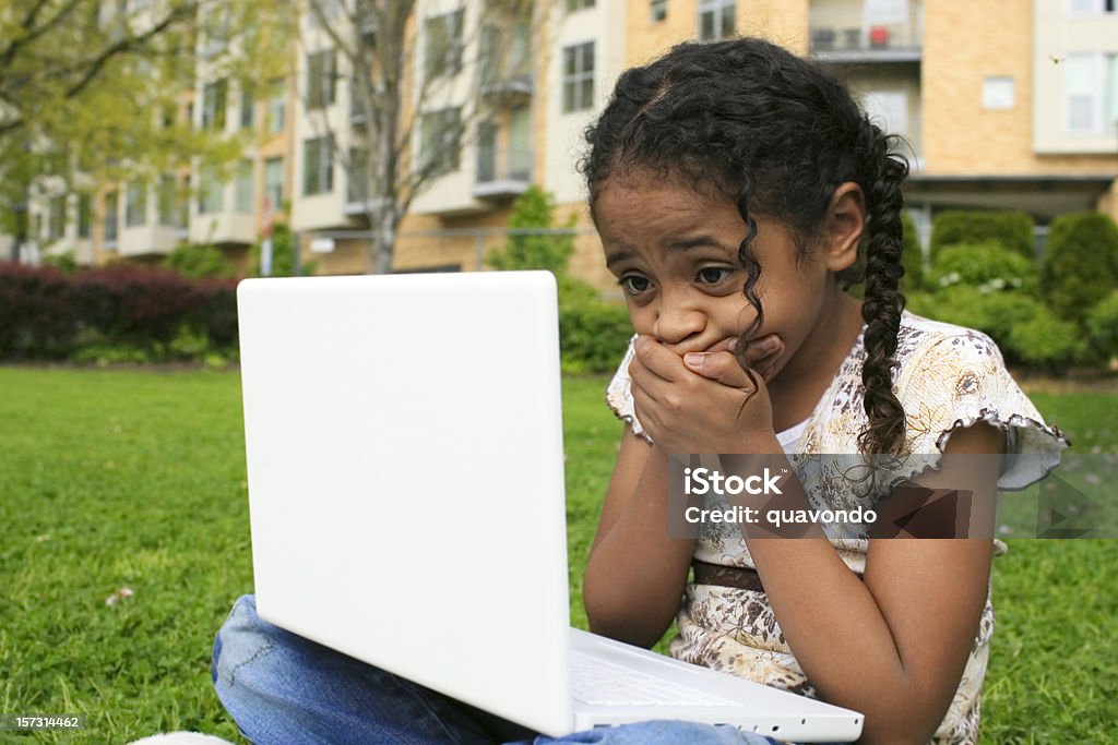 Афро-американских девочка с помощью ноутбука на улице, шок, охватывающий рот - Стоковые фото Компьютер роялти-фри