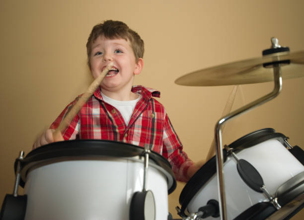 istock Boy in red checkered shirt happily playing the drums 157314800