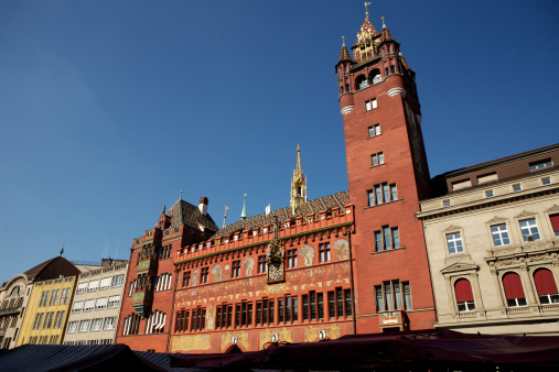 Close-up of red town hall with clock, paintings and ornaments in Basel, Switzerland