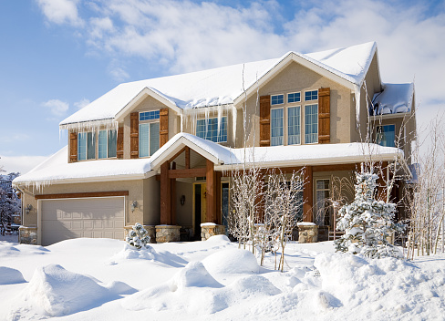 A snow covered luxury home under blue sky.