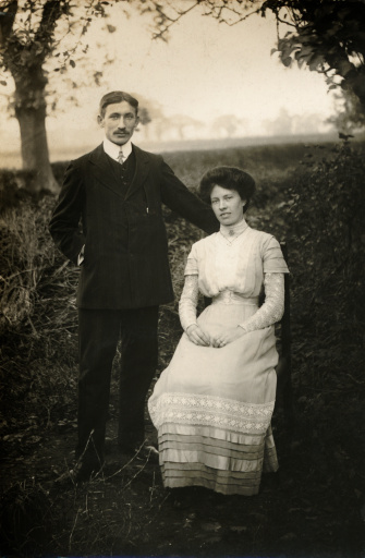 Portrait of smiling old husband and wife with arms crossed standing back to back on white background