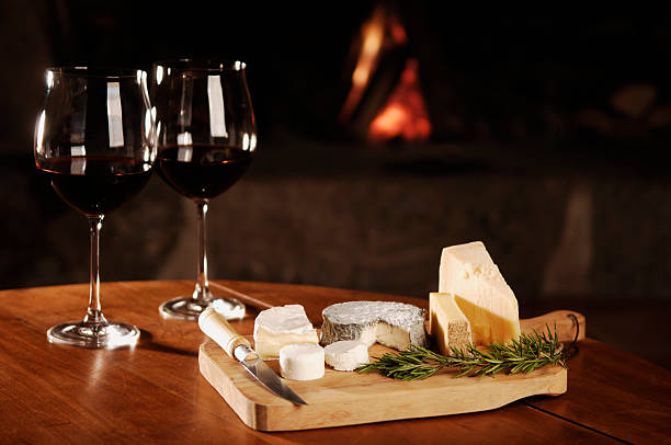red wine and cheese at fireplace stock photo