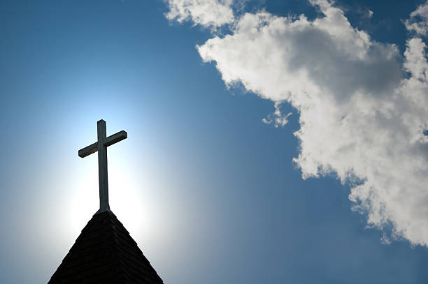 easter morning with the sun behind a church steepl cross. - christendom stockfoto's en -beelden