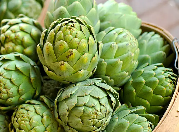 Fresh artichokes in a basket for sale at a market. (SEE LIGHTBOXES BELOW for more organic spring vegetables, fruits, meals & food backgrounds...)
