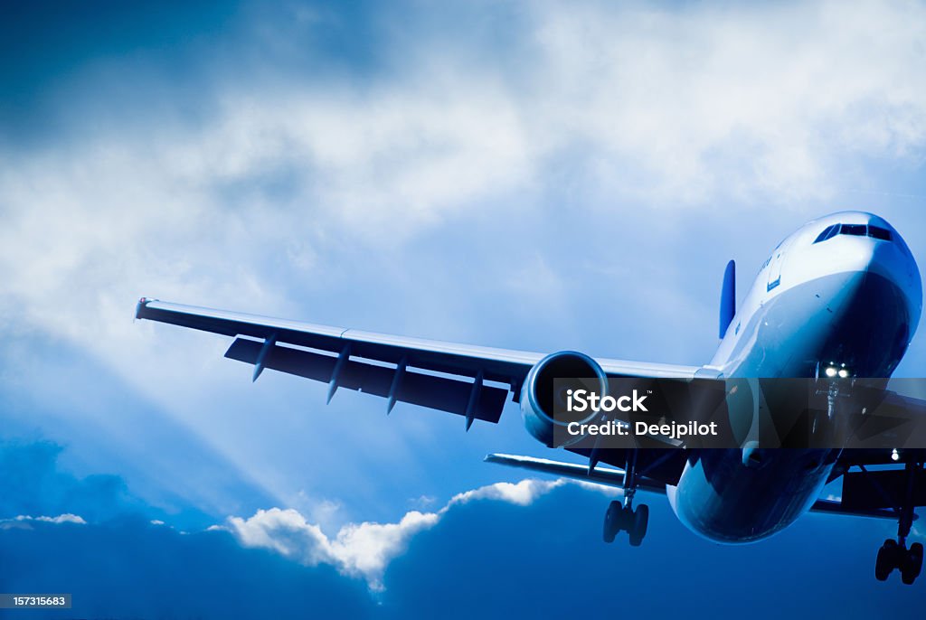 Airliner landing in a Storm Passenger Airliner overhead with stormy sky. Backlit, head on view showing left hand wing and aircraft fuselage.  Aircraft Wing Stock Photo