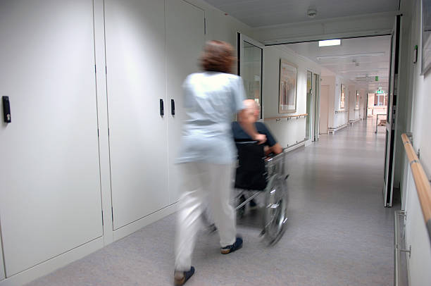 Nurse pulling a wheelchair stock photo