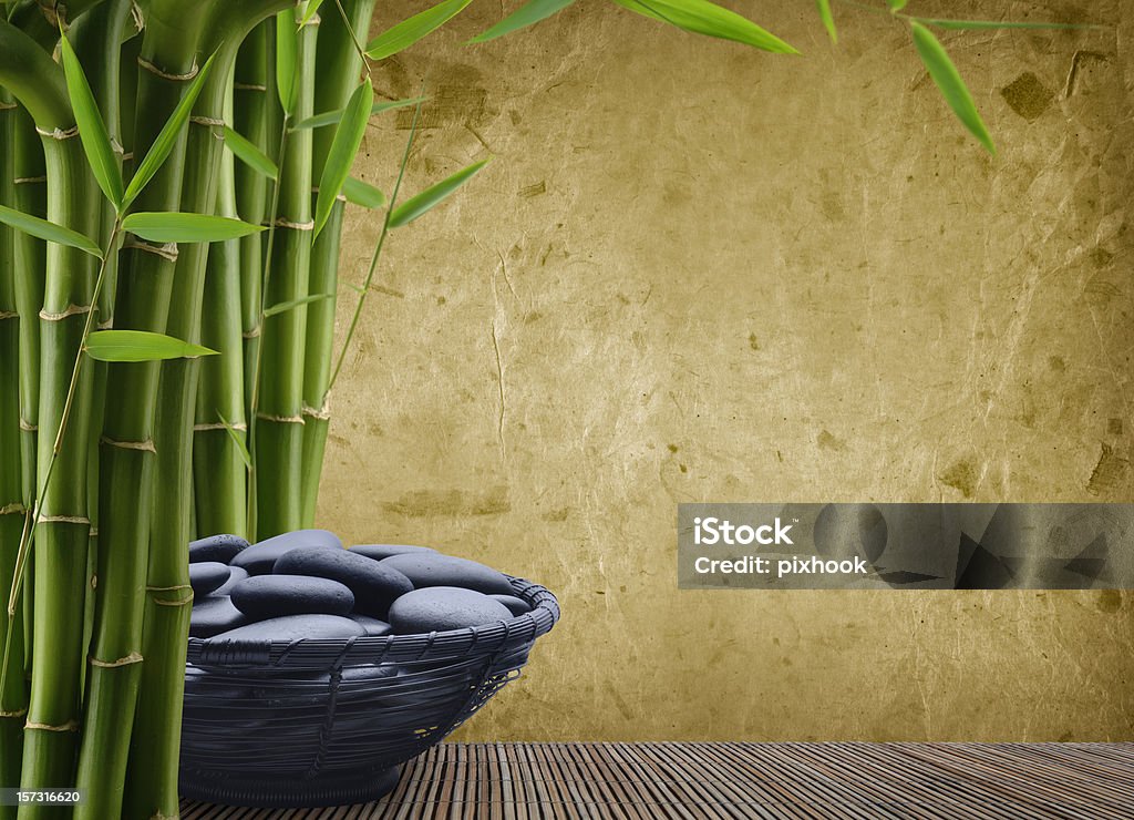 Massage Stones Massage Stones in Black Wire Basket with Bamboo and Rice Paper Background. Backgrounds Stock Photo