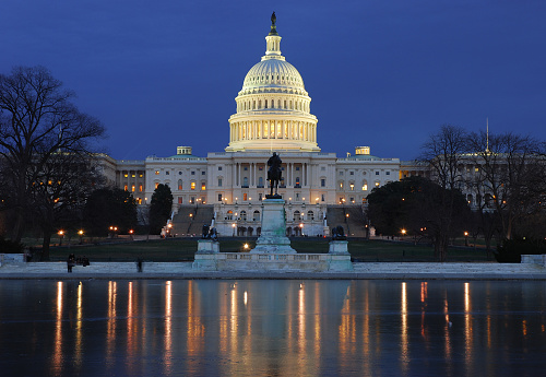 Illuminated US Capitol building with reflection on ice