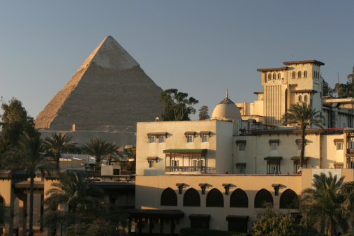 Morning sun hits the city buildings of Cairo which stand close to the Pyramid of Chephren or Khafre with a portion of its origianal limestone cladding. It is dated from the Old Kingdom, Dynasty IV c. 2500 B.C. located on the Giza Platau of Egypt.