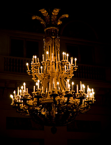 A round lamp with a rectangular iron frame suspended from the ceiling, illuminating in gold. Interior concept.