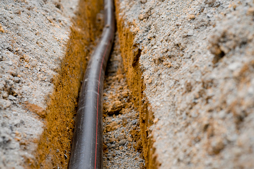 Newly laid pipe in a fresh trench.  Shallow depth of field