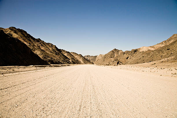 strada di campagna attraverso montagne - dirt road road desert road gravel foto e immagini stock