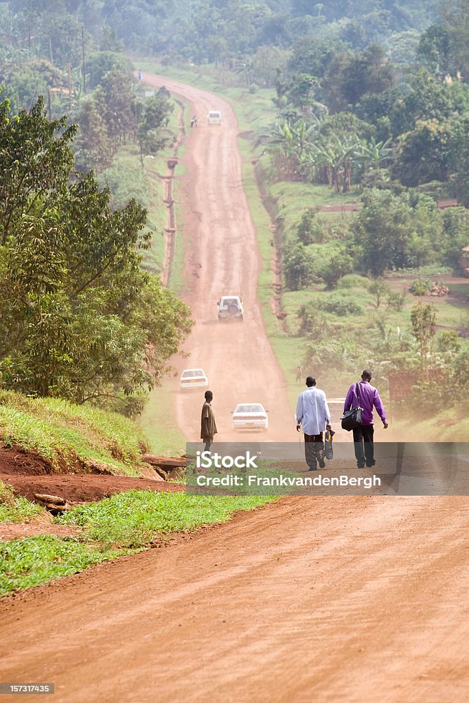 Gente caminando por un africano polvo y suciedad road. - Foto de stock de Uganda libre de derechos