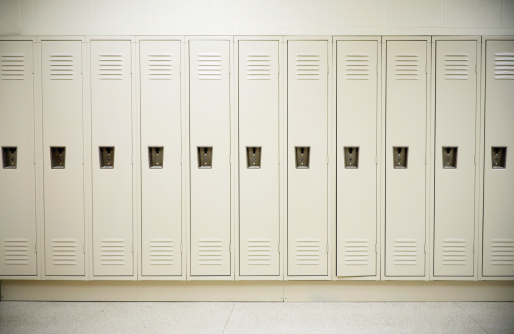 Row of tall white lockers in a white corridor
