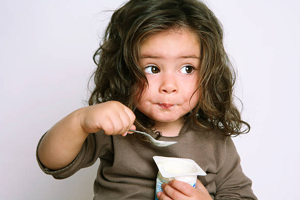 menina comer iogurte - child eating imagens e fotografias de stock