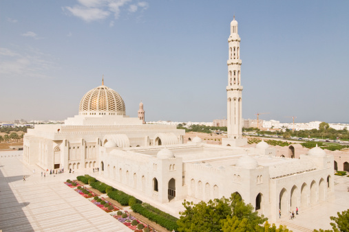The skyline of modern Fujairah with a mosque among the modern architecture and a historic Arabic building in the forefront in Fujairah, United Arab Emirates