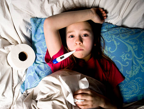 Sick Little Girl in Bed with Thermometer stock photo