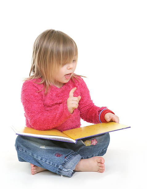 A little blonde girl learning to read Little girl sitting down to read a book short story stock pictures, royalty-free photos & images