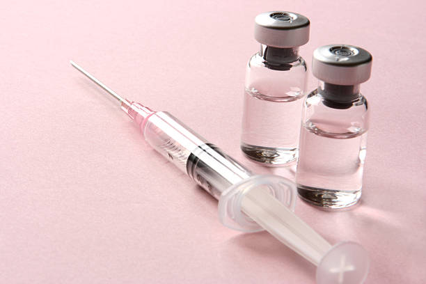 Vaccination: Syringe and Vials with Medicine This is a studio shot of two glass vials with medicine and a single syringe ready for an injection or vaccination on a light pink background with copy space. The vials and syringe could represent various healthcare and medicine concepts. medical injection stock pictures, royalty-free photos & images
