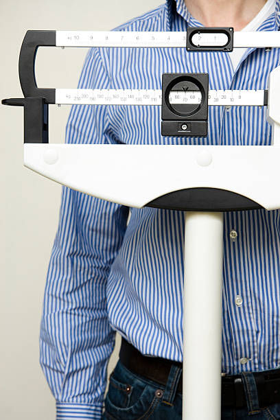 istock man on  medical weight scale 157318227