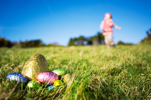 Young girl running towards Easter eggs. Low depth of field, focus in foreground.