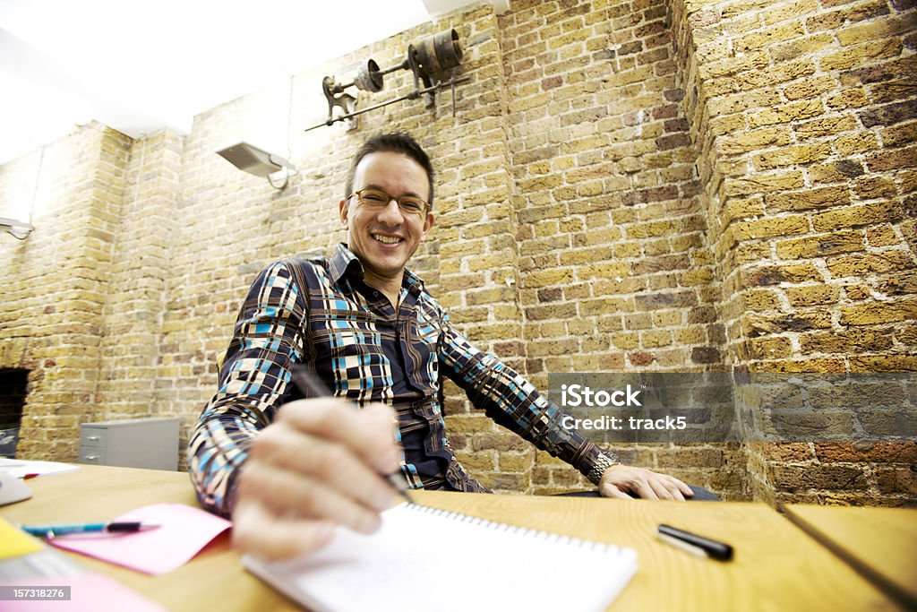 Fiducioso sorriso da un moderno professionista creativo alla sua scrivania - Foto stock royalty-free di Grandangolo - Tecnica fotografica