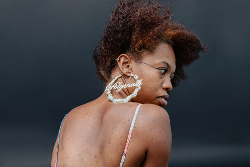 Fashionable and natural woman with her back turned showing off her 'Polymath' gold hoop earring